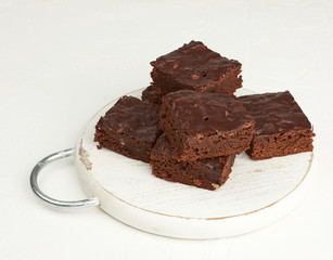 stack of square baked slices of brownie chocolate cake with walnuts