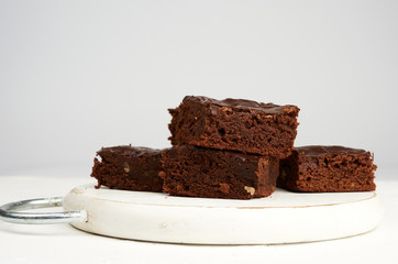stack of square baked slices of brownie chocolate cake with walnuts