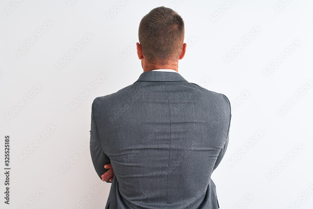 Wall mural Young handsome business man wearing suit and tie over isolated background standing backwards looking away with crossed arms