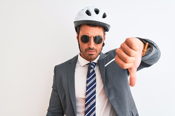 Young handsome business man wearing bike helmet and sunglasses over isolated background with angry...
