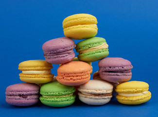 Fototapeta na wymiar stack of multi-colored round baked macarons cakes on a dark blue background