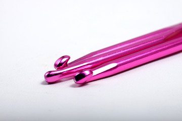 Pink metal crochet hook for knitting craft on an isolated white background