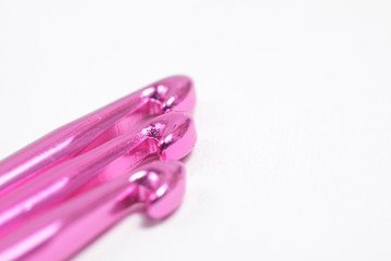 Pink metal crochet hook for knitting craft on an isolated white background