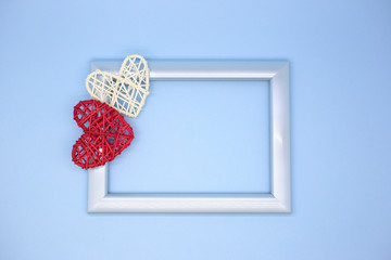 Blue photo frame on a blue background with red and white wooden hearts. Valentine's day greeting card. Love concept. Place for text