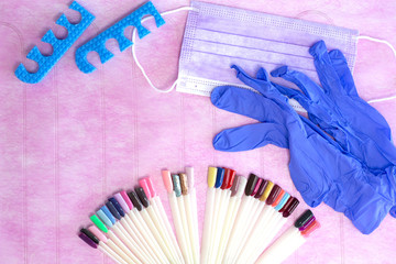 Pedicure utensils on pink background. Rubber gloves, dust mask, nail polish colours on palette. Chiropody accessories. Top view