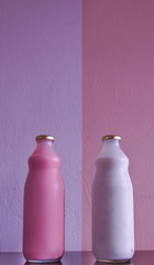 two glass bottles of white and pink yogurt with a bottom wall with the same colors, but inverted.