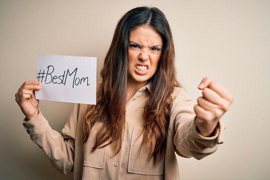 Young beautiful woman holding paper with best mom message celebrating mothers day annoyed and frustrated shouting with anger, crazy and yelling with raised hand, anger concept