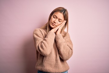 Young beautiful blonde woman wearing winter wool sweater over pink isolated background sleeping tired dreaming and posing with hands together while smiling with closed eyes.
