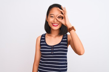 Obraz na płótnie Canvas Young chinese woman wearing striped t-shirt standing over isolated white background doing ok gesture shocked with surprised face, eye looking through fingers. Unbelieving expression.
