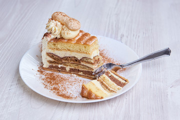 Tiramisu cake/ dessert with fork, cacao on a porcelain plate