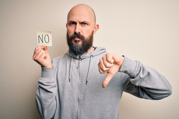 Handsome bald man with beard holding reminder paper with negative message with angry face, negative...