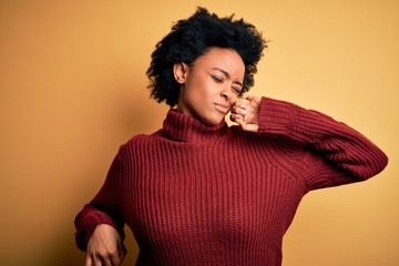 Fototapeta na wymiar Young beautiful African American afro woman with curly hair wearing casual turtleneck sweater stretching back, tired and relaxed, sleepy and yawning for early morning