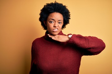 Fototapeta na wymiar Young beautiful African American afro woman with curly hair wearing casual turtleneck sweater cutting throat with hand as knife, threaten aggression with furious violence