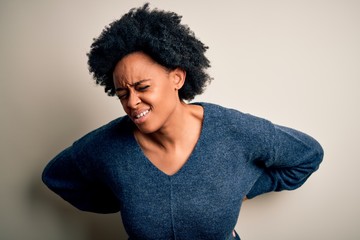 Fototapeta na wymiar Young beautiful African American afro woman with curly hair wearing casual sweater Suffering of backache, touching back with hand, muscular pain