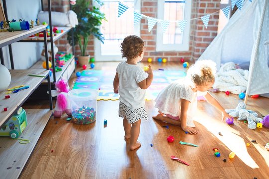 Beautiful toddlers playing around lots of toys at kindergarten