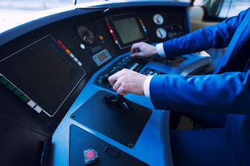 Shot of an unrecognizable professional driver in uniform operating in train cockpit and driving high speed train. Transportation services and occupation.
