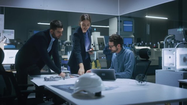 Modern Factory Office Meeting Room: Diverse Team of Engineers, Managers Talking at Conference Table, Look at Blueprints, Inspect Mechanism, Use Laptop. High-Tech Facility with CNC Machines