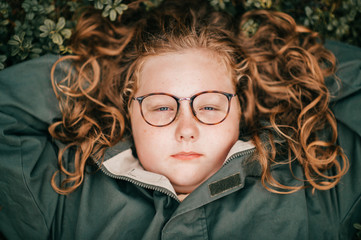 Portrait of pretty chubby girl with glasses lies on a grass