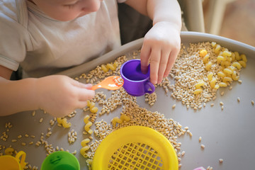 small kid pours toy yellow spoon ful in cup. Games with products. Montessori technique. development...