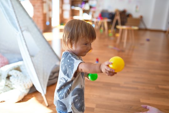 Adorable toddler playing around lots of toys at kindergarten