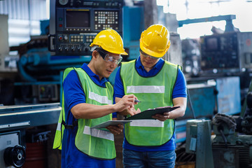 Industrial two men engineers in a factory checking documents