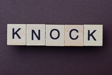 gray word knock from small wooden letters on a brown table