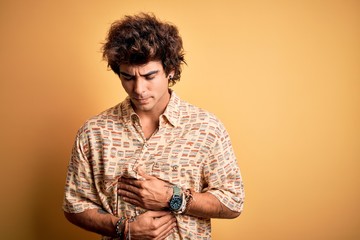 Young handsome man on vacation wearing summer shirt over isolated yellow background with hand on...
