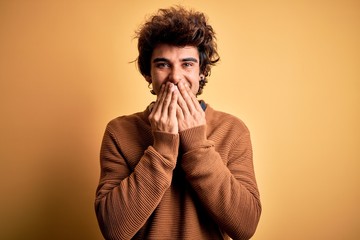 Young handsome man wearing casual shirt and sweater over isolated yellow background laughing and...