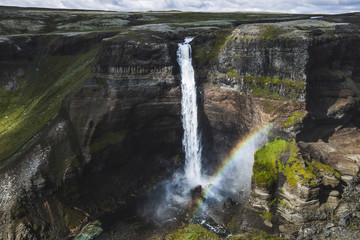 Aerial view of Haifoss big waterfall in south Iceland. Black high rocks, green hills, rainbow and nobody around. Sunny dramatic weather.