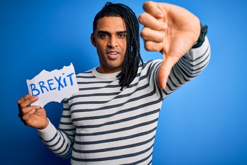 Fototapeta premium Young african american afro man holding banner with brexit message over blue background with angry face, negative sign showing dislike with thumbs down, rejection concept