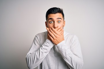Young handsome man wearing casual t-shirt standing over isolated white background shocked covering...