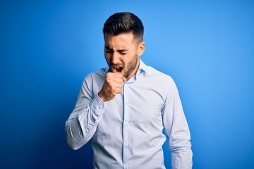 Young handsome man wearing elegant shirt standing over isolated blue background feeling unwell and coughing as symptom for cold or bronchitis. Health care concept.