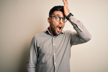 Young handsome man wearing elegant shirt and glasses over isolated white background surprised with...