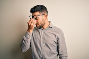 Young handsome man wearing elegant shirt and glasses over isolated white background tired rubbing...
