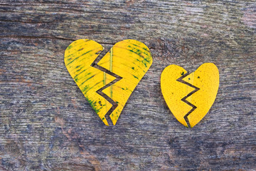 Two broken golden hearts on a natural wooden surface.