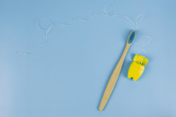 Toothbrush and dental floss on a blue background. Oral care concept. Caring for nature, zero waste....