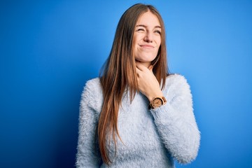 Young beautiful redhead woman wearing casual sweater over isolated blue background Touching painful neck, sore throat for flu, clod and infection