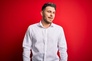Young business man with blue eyes wearing elegant shirt standing over red isolated background...