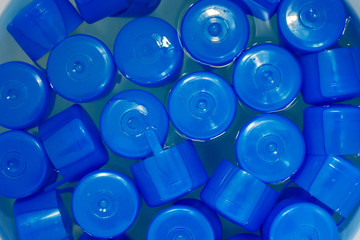 plastic blue bottle caps in water, top view, plastic cleaning and recycling