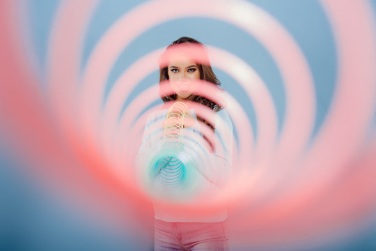 Happy teennager smiling for camera and playing with spring toy against blue background