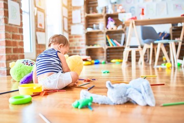 Adorable toddler playing around lots of toys at kindergarten