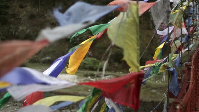 Buddhist prayer flags tied to a bridge, close up, shallow DOF