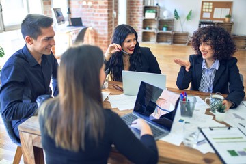 Group of business workers smiling happy and confident. Working together with smile on face  using laptop and speaking at the office