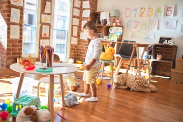 Adorable blonde twins playing around lots of toys at kindergarten