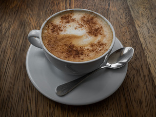 A cup of cappuccino coffee on wood