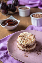 Grießflammerie aus Grieß mit Kakao und Sahne mit gekochtem Pflaumenmus und Pflaumen auf rosa ovalem Teller und Holz