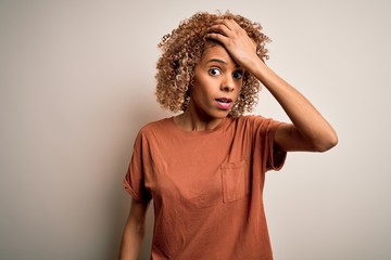 Beautiful african american woman with curly hair wearing casual t-shirt over white background...