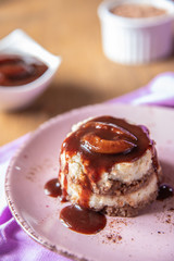 Grießflammerie aus Grieß mit Kakao und Sahne mit gekochtem Pflaumenmus und Pflaumen auf rosa ovalem Teller und Holz