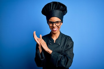 Young african american chef woman wearing cooker uniform and hat over blue background clapping and applauding happy and joyful, smiling proud hands together