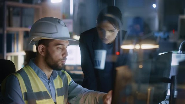 Modern Factory Office: Female Project Manager Talks to a Male Industrial Engineer who Works on Computer. Professional Teamwork, Specialists Solving Problems, Finding Solutions
